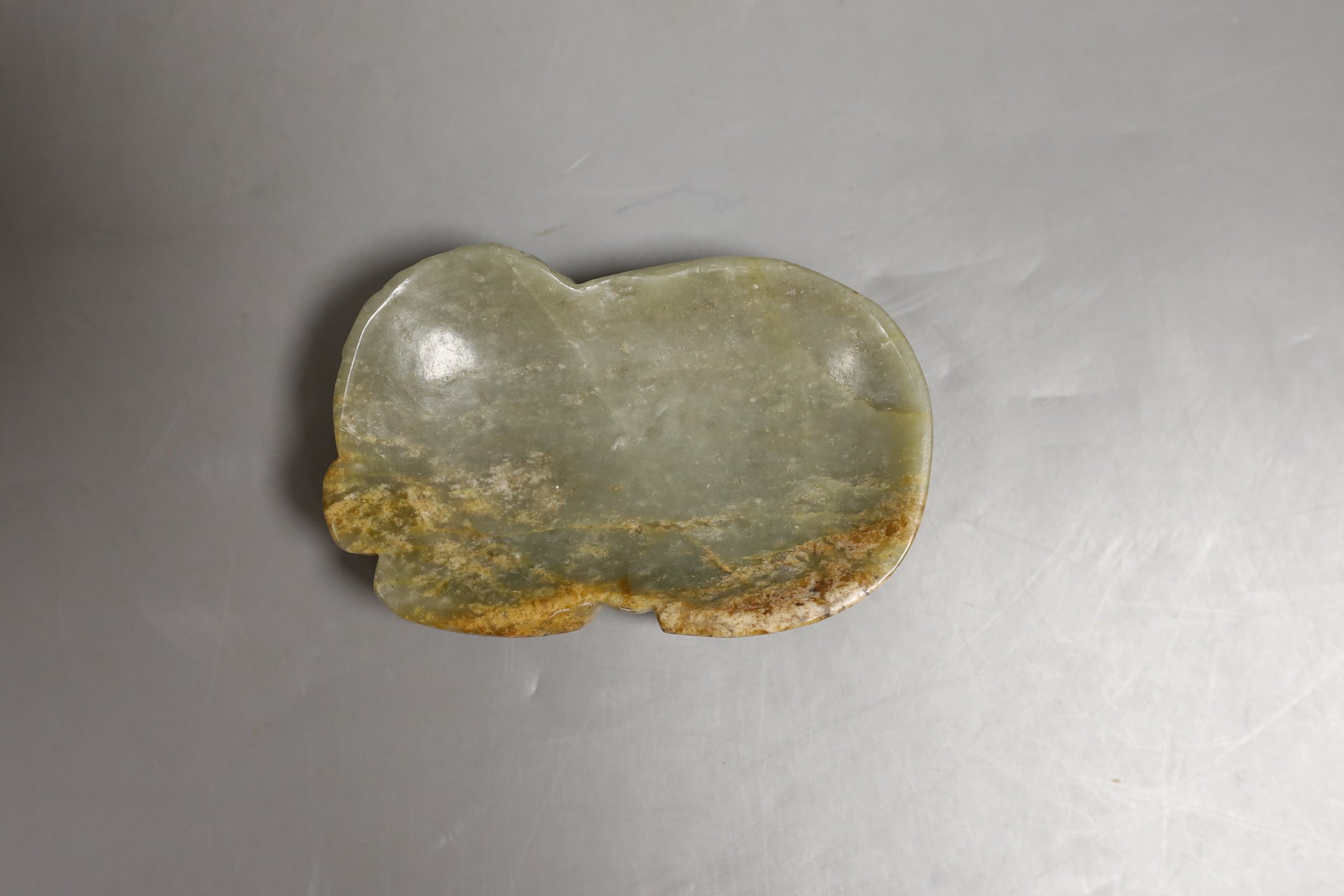 A Chinese celadon and a russet jade ‘lion dog and cub’ plaque, 11.5cm across